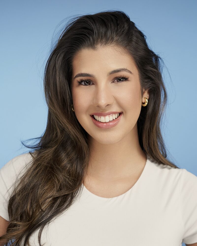 Jeannet Garcia commercial headshot — cream tee, blue backdrop, smiling