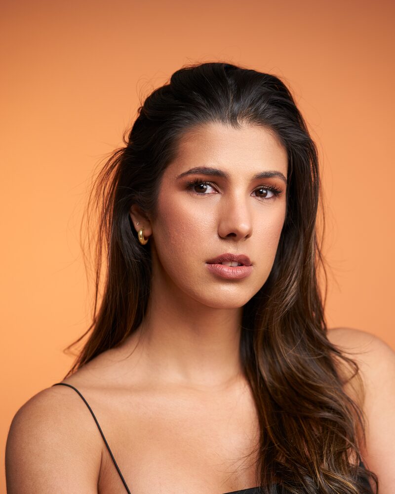 Jeannet Garcia headshot — black strappy top, warm orange backdrop